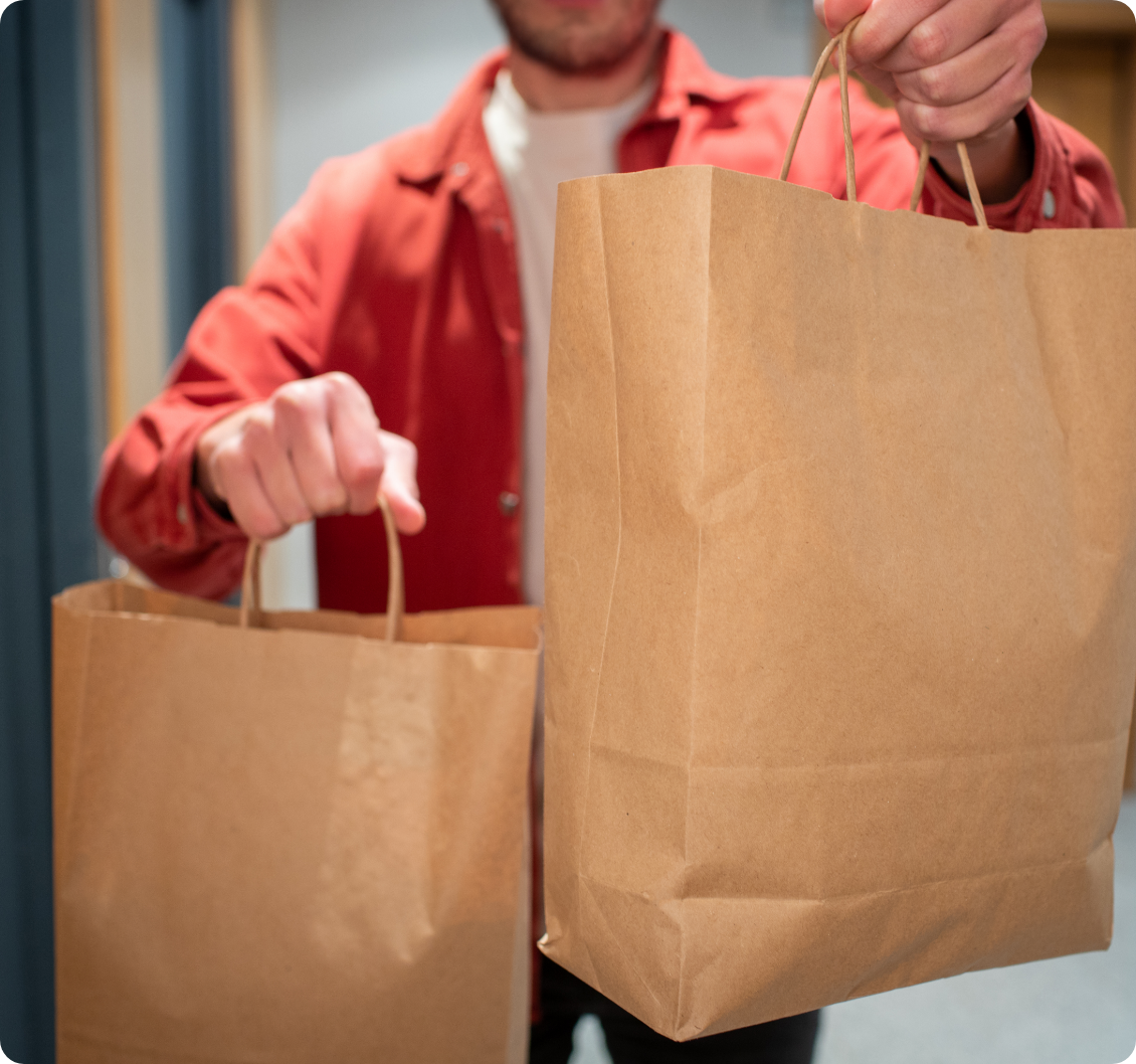 delivery-man-holding-paper-bag-with-food-entrance-courier-gives-box-with-fresh-vegetables-fruits-wine-customer Delivery Man Holding Paper Bag with Food